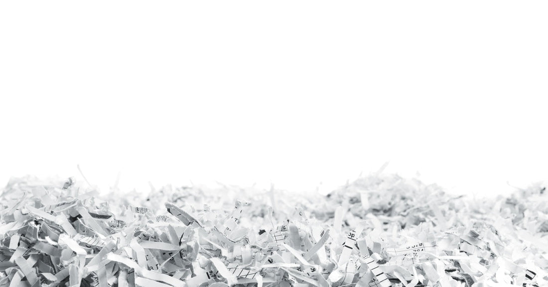 A heap of white shredded paper strips with small printed markings stretches across the bottom of a white background.