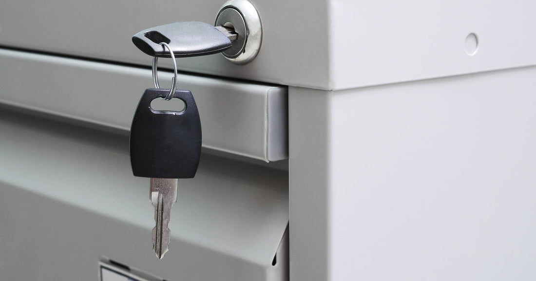 A close-up of a gray file cabinet with a lock positioned on the cabinet's frame. A key is twisted into the lock.