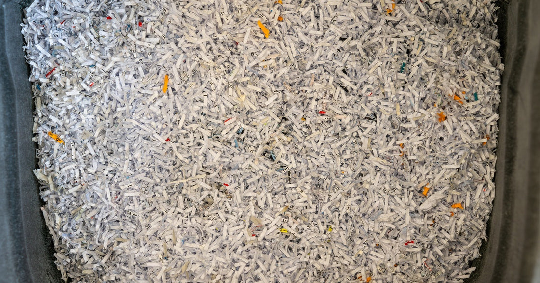 A close-up of white and yellow shredded strips of paper are in a large, gray bin that fills the frame.